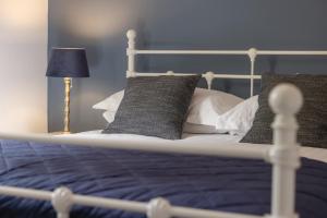 a bed with blue and white pillows and a lamp at The Green Man in Dunchurch