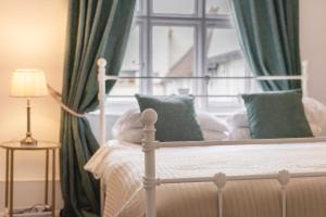 a white bed with green curtains and a window at The Green Man in Dunchurch