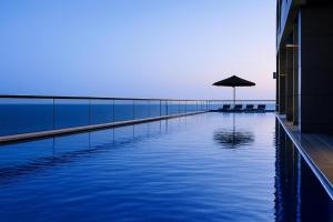 a swimming pool with an umbrella next to a building at AREAN Hotel Bat Yam in Bat Yam