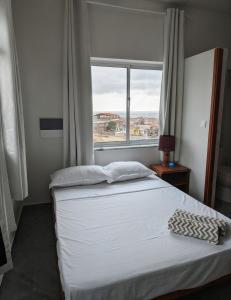a bed in a room with a large window at Mirage in Tarrafal