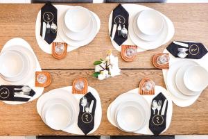 a table with white plates and utensils on it at Aurora 1BR - Coastal Chic Luxe Retreat in Abu Dhabi