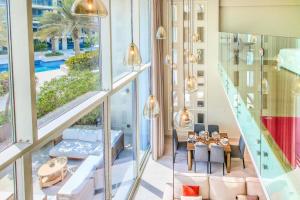 a living room with glass walls and a staircase at Aurora 1BR - Coastal Chic Luxe Retreat in Abu Dhabi +39 photos