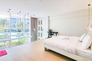a white bedroom with a bed and a large window at Aurora 1BR - Coastal Chic Luxe Retreat in Abu Dhabi