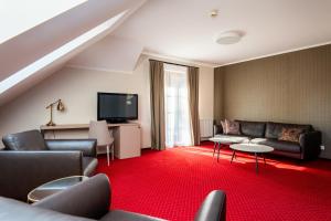 a living room with a couch and a tv at Hotel - Dworek Tryumf in Księżyno