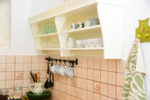 a kitchen with white cabinets and cups and utensils at Erdei Kisház Sümeg in Sümeg +20 photos