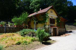 a small yellow house with a garden in front of it at Erdei Kisház Sümeg in Sümeg