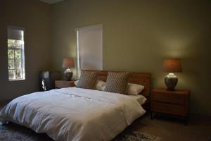 a bedroom with a bed with two nightstands and two lamps at Villa Euris Guesthouse in Brits