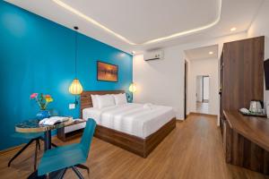 a bedroom with a bed and a desk and a table at Flora Hoi An Lantern Town in Hoi An