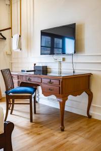 a desk with a television on a wall with a chair at Na Vayla PaPlern in Bangkok