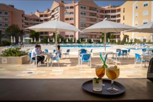 Ein Tablett mit zwei Getränken auf einem Tisch neben einem Pool in der Unterkunft Riviera Hotel in Carcavelos