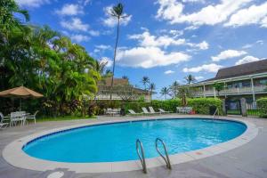 a swimming pool at a resort with chairs and a palm tree at Ideal Coconut Coast Condo in Kapaa