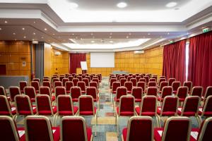 ein leerer Konferenzraum mit roten Stühlen und einem Rednerpult in der Unterkunft Riviera Hotel in Carcavelos + 52 Fotos