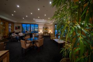 eine Lobby mit Menschen, die an Tischen sitzen, und Pflanzen in der Unterkunft Riviera Hotel in Carcavelos