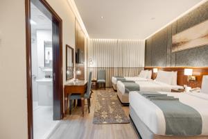 a hotel room with three beds and a desk at Maysan Rotana El Mysk Fully Renovated in Medina +25 photos