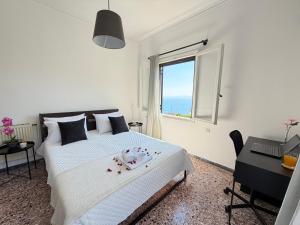 a white bedroom with a bed and a window at Demie and George Ηouse in Loutraki