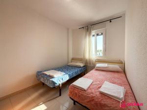 two beds in a room with a window at Poble Mar 2 in Oropesa del Mar