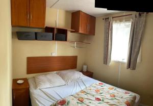 a bedroom with a bed and wooden cabinets and a window at Mobile Home Agde Les Sables D'or in Le Grau-dʼAgde