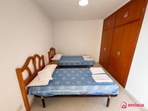 two twin beds in a small room with wooden cabinets at Poble Mar 2 in Oropesa del Mar