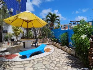 a yellow umbrella and a table and a blue chair at Pousada Chácara Porto do Sol in Jacumã