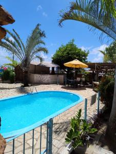 a swimming pool in a resort with an umbrella at Pousada Chácara Porto do Sol in Jacumã