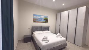 a bedroom with a white bed and a painting on the wall at Casa Varone del Vesuvio in Torre Annunziata