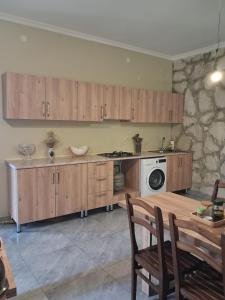 a kitchen with wooden cabinets and a table and a stove at Guest House Guliada in Gordi