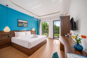 a bedroom with a large bed and a blue wall at Flora Hoi An Lantern Town in Hoi An