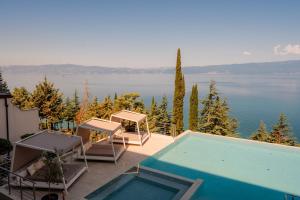 a swimming pool with chairs and a view of the water at Inex Olgica Hotel & SPA in Ohrid