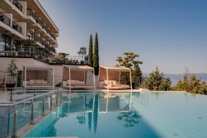 a swimming pool with two chairs and a building at Inex Olgica Hotel & SPA in Ohrid