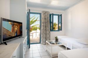 a living room with a white couch and a tv at Canvas by Mitsis Cretan Village in Hersonissos