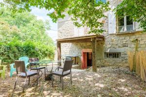 a patio with a glass table and chairs in front of a building at Appartement de charme en Ardèche in Aubenas