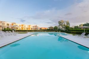 a large swimming pool with white chairs at Smy Pisa Plaza in Pisa