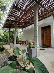 a patio with a wooden pergola and some plants at Dothalu Villa in Ahangama