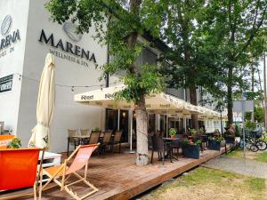 a restaurant with chairs and tables and a tree at Marena Wellness & Spa in Międzywodzie