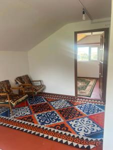 a room with a mirror and two chairs and a rug at Guest house Aibek in Kurmenty