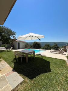 a table with an umbrella next to a pool at Vila Kala in Šmarje