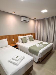 two beds in a hotel room with towels on them at Uai Hotel Jaíba in Terra Fôfa +18 photos