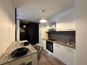 a kitchen with white cabinets and a table with glasses on it at L'échiquier royal-Studio chic proche château fort in Sedan