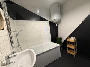 a bathroom with a bath tub and a sink at L'échiquier royal-Studio chic proche château fort in Sedan