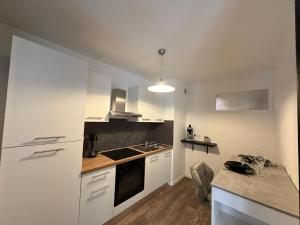 a kitchen with white cabinets and a counter top at L'échiquier royal-Studio chic proche château fort in Sedan +8 photos