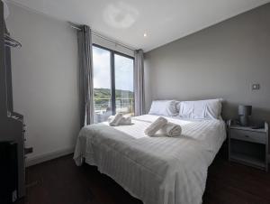 a bedroom with a white bed with a large window at Casa Brighouse in Brighouse