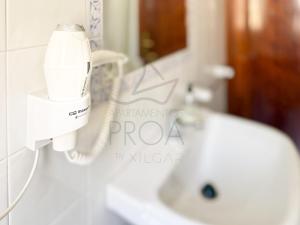 a bathroom with a hair dryer and a sink at Xilgar Apto Proa 2d encima de la playa in Raxó