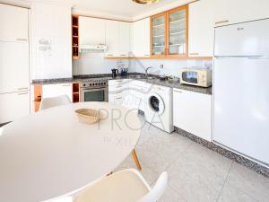 a white kitchen with a white table and chairs at Xilgar Apto Proa 2d encima de la playa in Raxó +7 photos