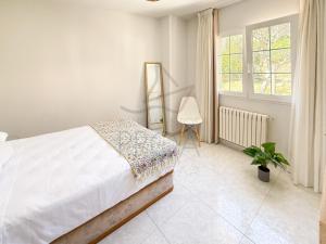 a white bedroom with a bed and a window at Xilgar Apto Proa 2d encima de la playa in Raxó