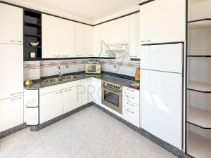a white kitchen with white cabinets and appliances at Xilgar Apto Proa 2d encima de la playa in Raxó