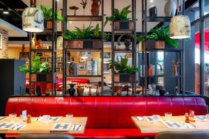 a red bench in a restaurant with plants at Novotel Grenoble Nord Voreppe in Voreppe
