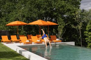 a man jumping into a swimming pool with an umbrella at Passinhos House in Amarante