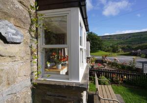a window of a house with a bench and flowers at Stony Thwaite in Reeth