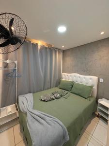 a bedroom with a bed with green sheets and a fan at Pousada - Aconchego da tia Zeni in Mangaratiba