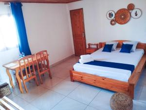 a bedroom with a bed and a table and chairs at Les Jardins d'Areca in Antsirabe